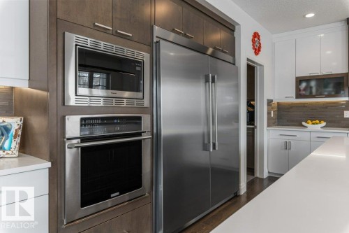 Kitchen Features Dark Hardwood Flooring, Two Tone Kitchen Cabinets, Gas Stove, Wall Oven, and White Quartz Counters - 4476 Suzanna Crescent, Edmonton, AB - Indoor Photo Showing Kitchen With Upgraded Kitchen