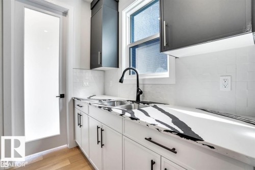 The property features a kitchen area with white cabinetry, a dual-basin sink with a matte black faucet, and a white countertop with black veining - 47 Rosewood Way, St. Albert, AB - Indoor Photo Showing Kitchen With Upgraded Kitchen