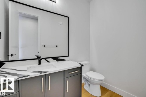 The property features a modern bathroom with a vanity, an integrated sink, a dark-toned faucet, and a toilet - 47 Rosewood Way, St. Albert, AB - Indoor Photo Showing Bathroom