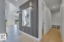 The property features light-colored hardwood flooring throughout the main areas, a contemporary wall paneling design with integrated sconces, and a built-in bench with coat hooks in a hallway - 47 Rosewood Way, St. Albert, AB  - Indoor Photo Showing Other Room 