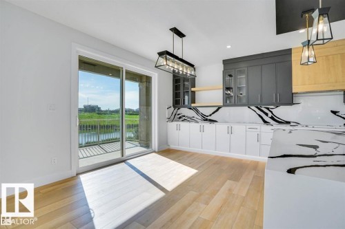 This property features light-toned hardwood flooring, a contemporary kitchen with dark cabinetry, white lower cabinets, and countertops with striking black veining - 47 Rosewood Way, St. Albert, AB - Indoor