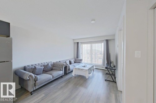Living area featuring light-colored flooring, white walls, and a sliding glass door with vertical blinds - 429 390 Windermere Rd, Edmonton, AB - Indoor