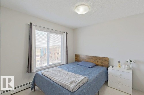 This room features a window with blinds and curtains, a ceiling light fixture, and baseboard heating - 429 390 Windermere Rd, Edmonton, AB - Indoor Photo Showing Bedroom