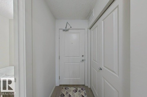 The property features a front entry with a white paneled door, light wood flooring, and a closet with white paneled bifold doors - 429 390 Windermere Rd, Edmonton, AB - Indoor Photo Showing Other Room