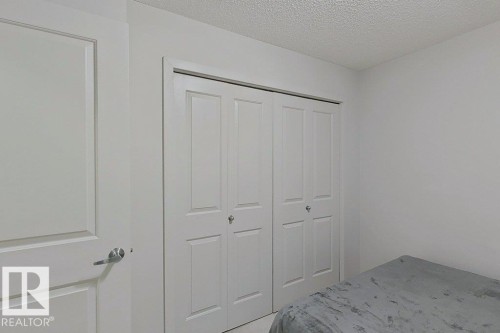 This room features white walls, a white door with a brushed nickel handle, and a closet with white bi-fold doors - 429 390 Windermere Rd, Edmonton, AB - Indoor Photo Showing Bedroom