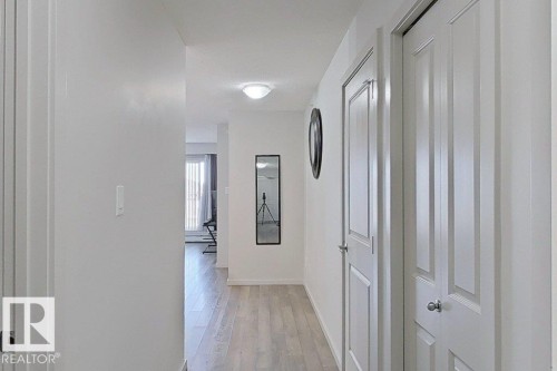 This hallway features light-toned flooring and white walls, creating a bright and open atmosphere - 429 390 Windermere Rd, Edmonton, AB - Indoor Photo Showing Other Room