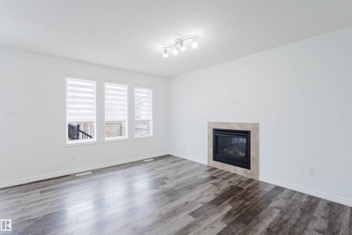 Unfurnished living room featuring a tile fireplace, a textured ceiling, and dark wood-type flooring - Edmonton, AB - Indoor Photo Showing Living Room With Fireplace