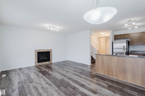 Unfurnished living room featuring rail lighting, a tile fireplace, and dark wood-style floors - Edmonton, AB - Indoor With Fireplace