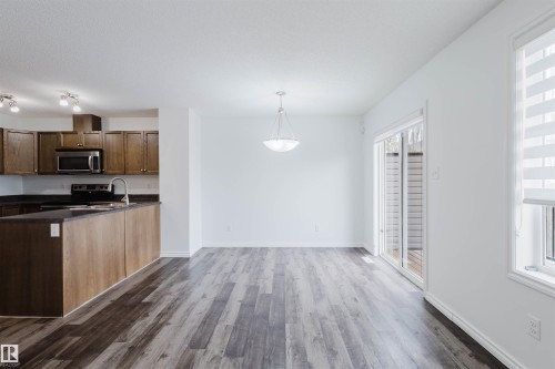 Kitchen featuring stainless steel appliances, dark wood finished floors, pendant lighting, dark stone countertops, and a peninsula - Edmonton, AB - Indoor Photo Showing Kitchen