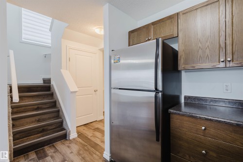 Kitchen with dark countertops, freestanding refrigerator, dark wood-style flooring, a textured ceiling, and wood finish cabinetry - Edmonton, AB - Indoor