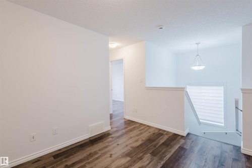 Empty room featuring dark wood-style flooring and a textured ceiling - Edmonton, AB - Indoor Photo Showing Other Room