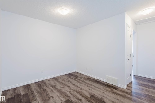 Spare room featuring a textured ceiling and dark wood-style floors - Edmonton, AB - Indoor Photo Showing Other Room