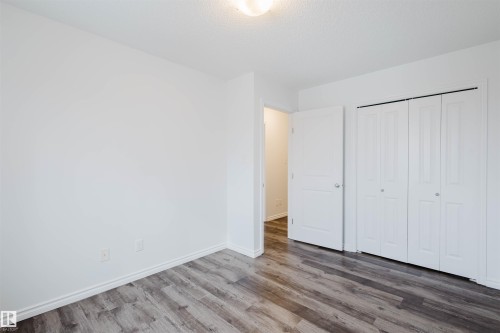 Unfurnished bedroom with wood finished floors, a closet, and a textured ceiling - Edmonton, AB - Indoor Photo Showing Other Room