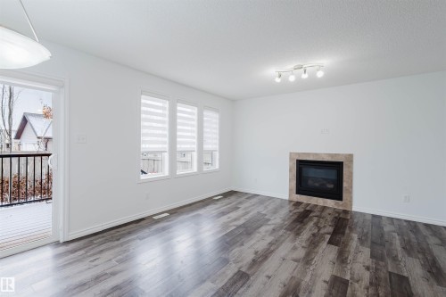 Unfurnished living room featuring a tile fireplace, dark wood-type flooring, and a textured ceiling - Edmonton, AB - Indoor Photo Showing Living Room With Fireplace