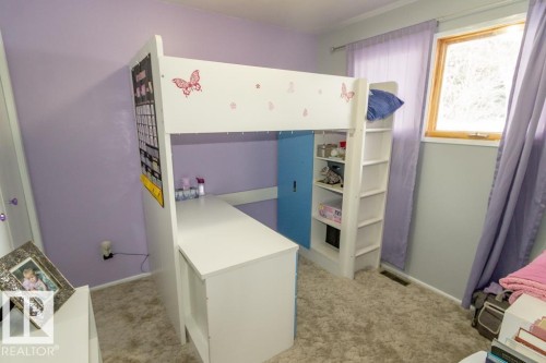 This room features a window with light-colored wooden trim, plush carpeting, and light purple walls - 5016 47 St, Myrnam, AB - Indoor