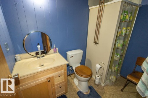 Bathroom featuring a vanity with an integrated sink and a circular mirror - 5016 47 St, Myrnam, AB - Indoor Photo Showing Bathroom