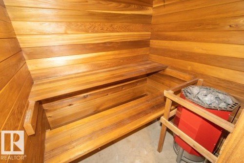 This sauna features wooden walls and benches, with a red heating unit containing rocks - 5016 47 St, Myrnam, AB - Indoor Photo Showing Other Room