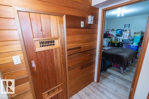 This room features extensive wood paneling and a wood door with vents - 5016 47 St, Myrnam, AB - Indoor Photo Showing Other Room