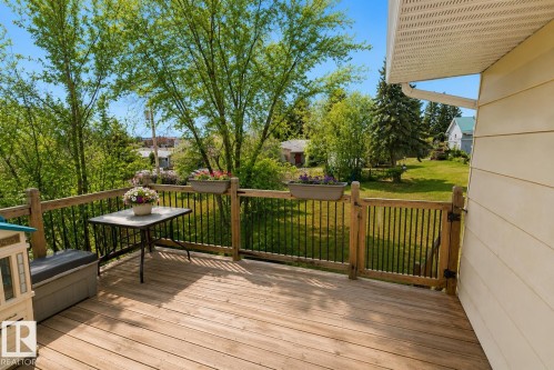 Expansive outdoor wooden deck featuring a wooden railing with black spindles and a functional gate - 5016 47 St, Myrnam, AB - Outdoor With Deck Patio Veranda With Exterior