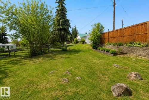 Expansive green lawn featuring mature trees and a wooden privacy fence - 5016 47 St, Myrnam, AB - Outdoor
