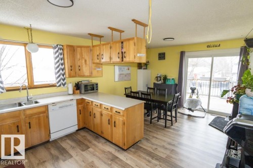 The kitchen features abundant natural wood cabinetry, light countertops, and durable flooring, with a window over the sink - 5016 47 St, Myrnam, AB - Indoor Photo Showing Kitchen With Double Sink