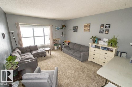 Spacious living area featuring light gray walls, a large window, and carpeted flooring - 5016 47 St, Myrnam, AB - Indoor Photo Showing Living Room