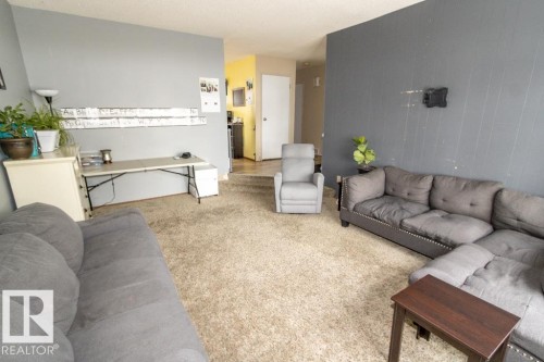 This living area features light-colored carpeting, and walls painted in shades of gray - 5016 47 St, Myrnam, AB - Indoor Photo Showing Living Room