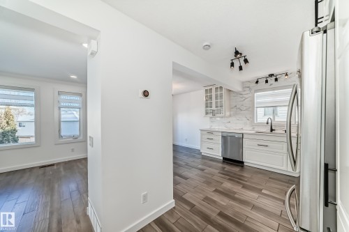 Kitchen with white cabinets, dark wood-style floors, stainless steel appliances, and light stone countertops - 4008 37 Avenue, Edmonton, AB - Indoor Photo Showing Kitchen