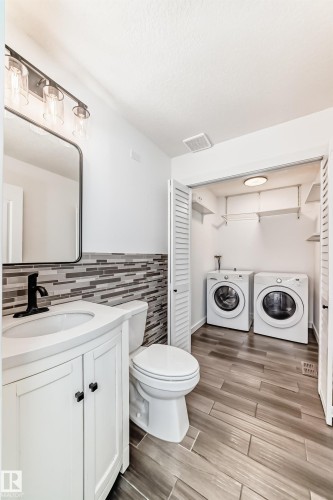 Half bathroom featuring vanity, independent washer and dryer, wood tiled floors, and a closet - 4008 37 Avenue, Edmonton, AB - Indoor Photo Showing Laundry Room