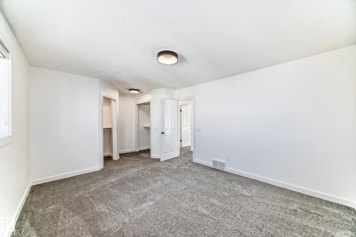 Unfurnished bedroom with a spacious closet, dark carpet, and a textured ceiling - 4008 37 Avenue, Edmonton, AB - Indoor Photo Showing Other Room
