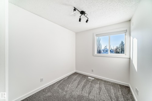 Unfurnished room featuring rail lighting, dark colored carpet, and a textured ceiling - 4008 37 Avenue, Edmonton, AB - Indoor Photo Showing Other Room