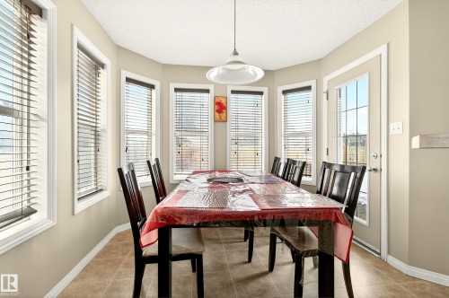 The dining area features bay windows, tiled flooring, and a glass-paned door providing outdoor access - 8922 5 Avenue, Edmonton, AB - Indoor Photo Showing Dining Room