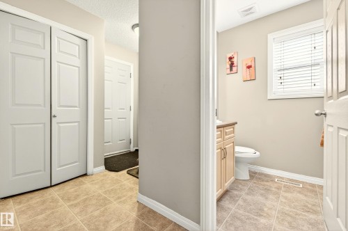 The property features tile flooring throughout the hallway and bathroom, a bathroom vanity with a countertop and under-sink cabinetry, and a window with blinds - 8922 5 Avenue, Edmonton, AB - Indoor