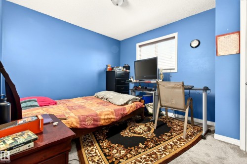 This room features bright blue walls and a window with blinds, allowing for natural light - 8922 5 Avenue, Edmonton, AB - Indoor Photo Showing Bedroom