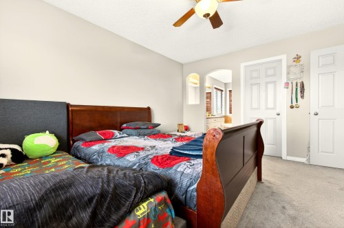This bedroom features soft grey carpeting, light-colored walls, and a ceiling fan with an integrated light fixture - 8922 5 Avenue, Edmonton, AB - Indoor Photo Showing Bedroom
