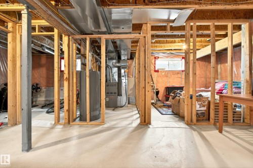 The unfinished basement features exposed wooden framing, concrete flooring, and a visible water heater and furnace - 8922 5 Avenue, Edmonton, AB - Indoor Photo Showing Basement