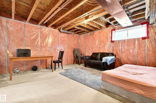 The property features an unfinished basement with exposed wood joists and structural elements, insulated walls, and a window for natural light - 8922 5 Avenue, Edmonton, AB - Indoor Photo Showing Basement