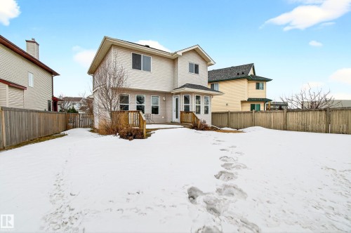 The property features a two-story exterior with light-colored siding, a wooden deck, and a fenced yard - 8922 5 Avenue, Edmonton, AB - Outdoor
