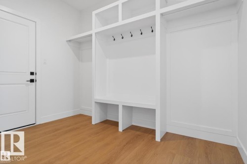Entryway featuring light wood flooring, a white door with black hardware, and built-in white shelving with hooks for storage - 5 Rosa Crescent, St. Albert, AB - Indoor