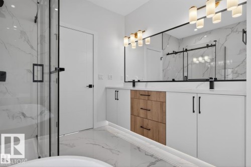 Modern bathroom featuring a double vanity with white cabinetry and wooden drawers, a large mirror with integrated lighting, and a glass-enclosed shower with a white bathtub - 5 Rosa Crescent, St. Albert, AB - Indoor
