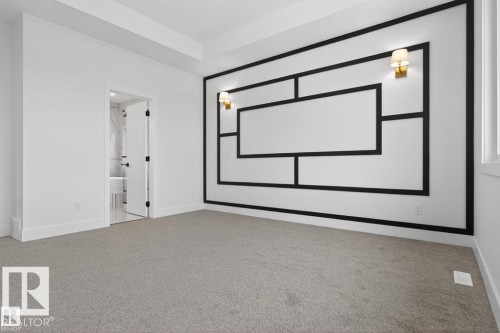 Spacious room featuring carpeted flooring, a decorative accent wall with sconce lighting, and a doorway leading to an adjoining bathroom - 5 Rosa Crescent, St. Albert, AB - Indoor Photo Showing Other Room
