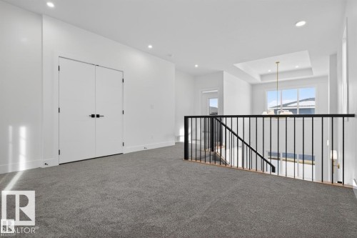 Open concept area featuring grey carpeting, white walls, and a modern black metal and wood railing - 5 Rosa Crescent, St. Albert, AB - Indoor Photo Showing Other Room