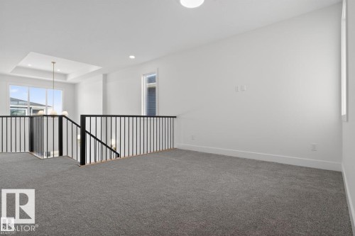 This versatile loft space features plush grey carpeting, white walls, and a contemporary black metal railing - 5 Rosa Crescent, St. Albert, AB - Indoor Photo Showing Other Room