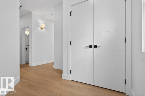Hallway featuring light wood-style flooring, white walls, and modern white doors with black hardware - 5 Rosa Crescent, St. Albert, AB - Indoor Photo Showing Other Room
