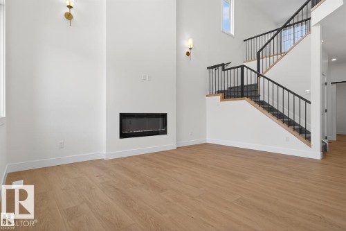 Living area featuring light wood flooring, a contemporary fireplace, and a staircase with black railings - 5 Rosa Crescent, St. Albert, AB - Indoor With Fireplace