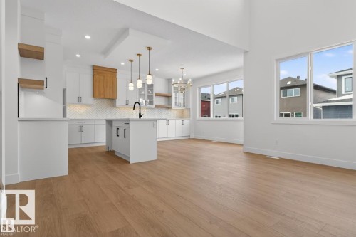 Open concept living area with light wood-style flooring and large windows, offering ample natural light - 5 Rosa Crescent, St. Albert, AB - Indoor Photo Showing Kitchen With Upgraded Kitchen