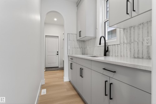 The property features a kitchen area with light grey cabinetry, a light-colored countertop, and a white tiled backsplash - 11 Redbud Way, St. Albert, AB - Indoor