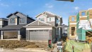 Two-story residence featuring a two-car garage with a textured door, a combination of horizontal siding and shingle accents, and decorative stone veneer on the lower facade - 11 Redbud Way, St. Albert, AB  - Outdoor With Facade 