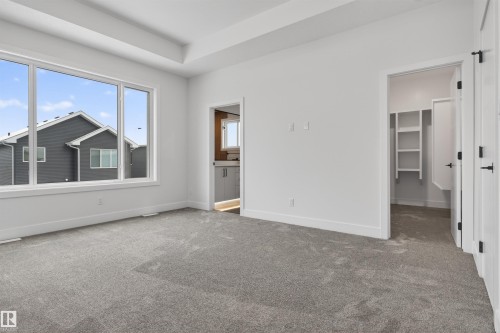 The property features a spacious room with light gray carpeting and a large window providing ample natural light - 11 Redbud Way, St. Albert, AB - Indoor Photo Showing Other Room