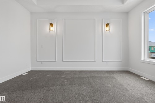 This room features stylish wall sconces, decorative wall trim, and a window providing natural light - 11 Redbud Way, St. Albert, AB - Indoor Photo Showing Other Room